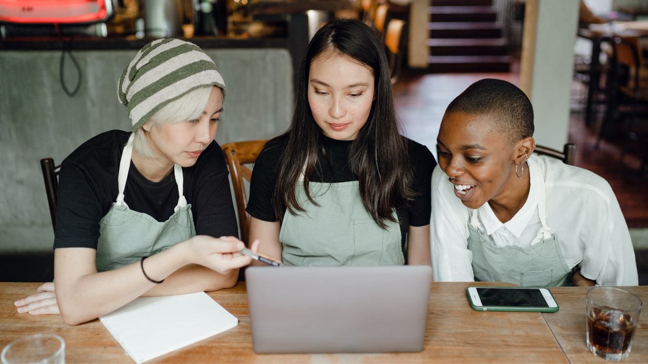 Small business owner and managers review business documents on laptop